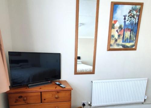 a television on a dresser with two mirrors on a wall at Wentworth Apartment with 2 bedrooms, Superfast Wi-Fi and Parking in Sittingbourne