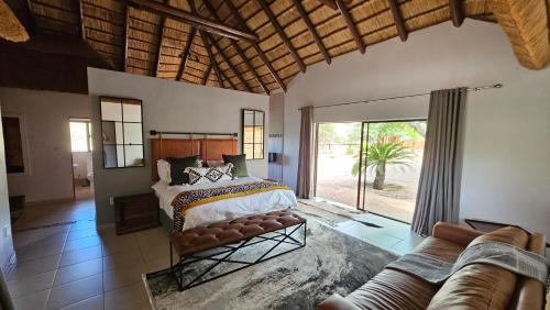 a bedroom with a bed and a couch in it at Makhato Bush Lodge 48 in Bela-Bela