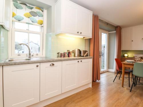 a kitchen with white cabinets and a table and a window at Timley Knott in Coniston