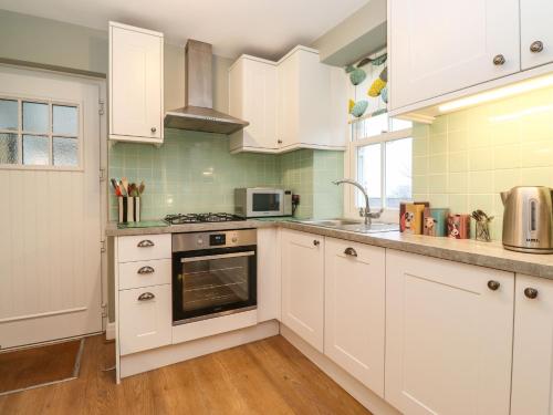 a kitchen with white cabinets and a stove top oven at Timley Knott in Coniston