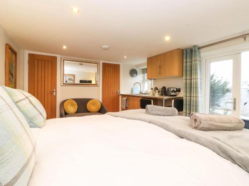 a bedroom with two large white beds and a kitchen at Timley Knott in Coniston