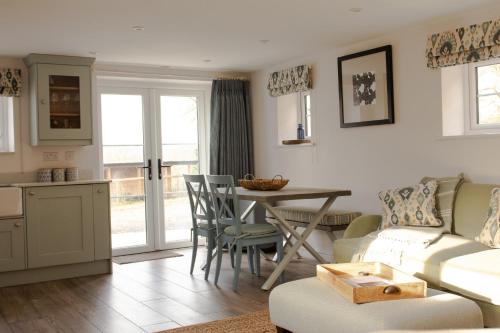 a kitchen and living room with a table and a couch at Finwood Green Farm Holiday Cottages-The Calf Shed and The Milk Parlour in Henley in Arden