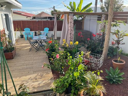 a wooden deck with a table and chairs and flowers at La Kaz Hibiscus, jacuzzi privé in Le Tampon