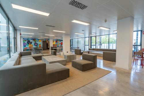 a lobby with couches and tables in a building at Micampus Alicante Student Residence in San Vicente del Raspeig