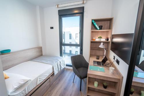 a bedroom with a bed and a desk with a laptop at Micampus Alicante in San Vicente del Raspeig