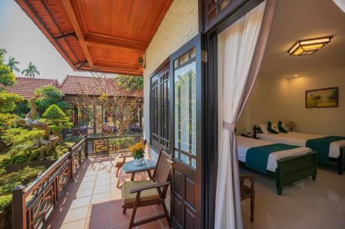 a room with two beds and a balcony at Betel Garden Villa in Hoi An