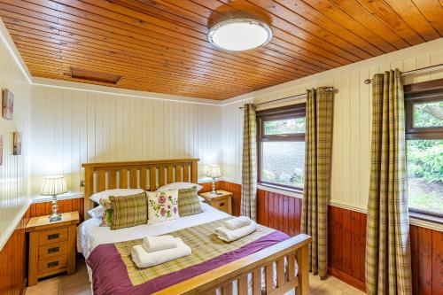 um quarto com uma cama e um tecto de madeira em Bluebell Lodge 2 with Hot Tub em Newton Stewart