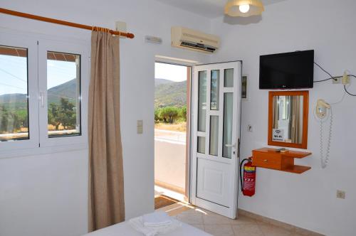 a room with a door and a tv and a window at Lagos Studios & Apartments in Palekastron