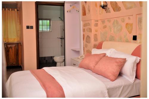 a bedroom with a white bed with a pink pillow at Ruby Haven in Kampala
