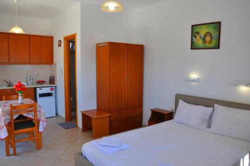 a bedroom with a bed and a kitchen with a table at Lagos Studios & Apartments in Palekastron