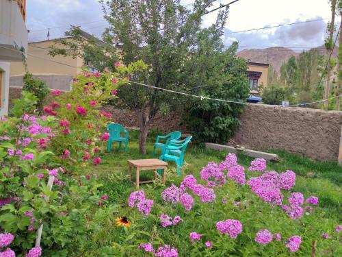 two chairs and a table in a garden with flowers at Chakzot garden house in Leh