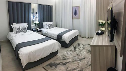 ein Hotelzimmer mit 2 Betten und einem TV in der Unterkunft ناصرية العليا in Khobar