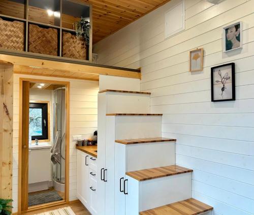 a tiny house with white walls and wooden floors at Tiny house with garden and jacuzzi near Amsterdam in Vijfhuizen