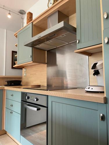 - une cuisine avec des placards bleus et une cuisinière dans l'établissement L'Appart sur Jardin 42m2 très calme, à La Rochelle