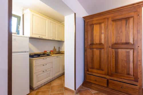 a kitchen with white cabinets and a wooden door at Casa Ulmi con piscina in Uggiano la Chiesa
