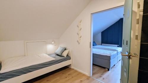 1 dormitorio pequeño con 2 camas y puerta en Moderne Ferienwohnung mit Südbalkon in der Nähe der Stever, en Lüdinghausen