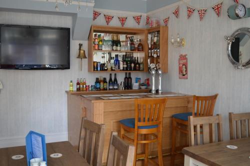 a kitchen with a bar with chairs and a tv at The Rookery in Swanage