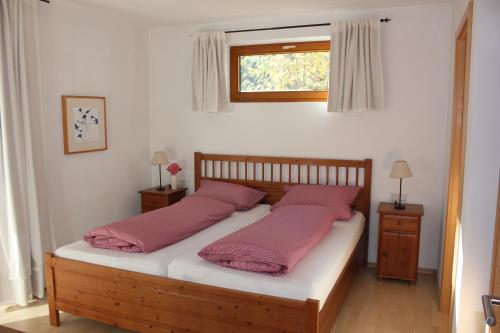 um quarto com uma cama com almofadas cor-de-rosa e uma janela em Ferienwohnungen Almrausch em Oberammergau