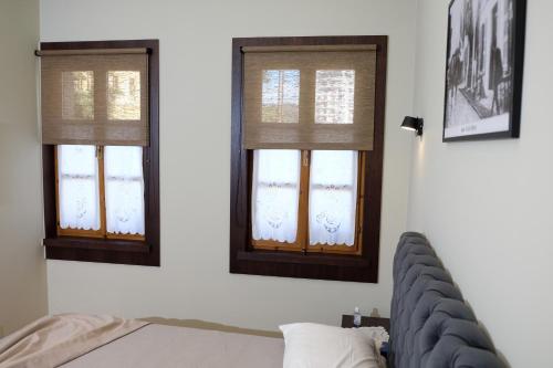 2 Fenster in einem Schlafzimmer mit einer Couch davor in der Unterkunft Tebeu coffe and bar in Vlorë