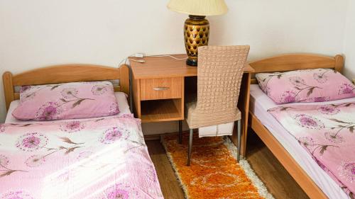 a bedroom with two beds and a desk with a lamp at apartment HOME in Bihać