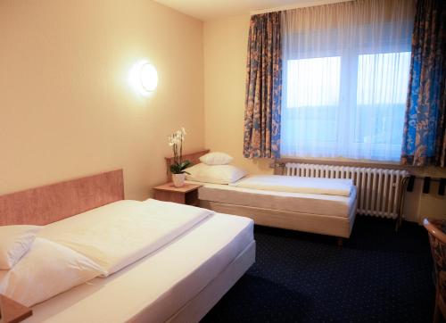 a hotel room with two beds and a window at Friends Hotel Kerpen in Kerpen