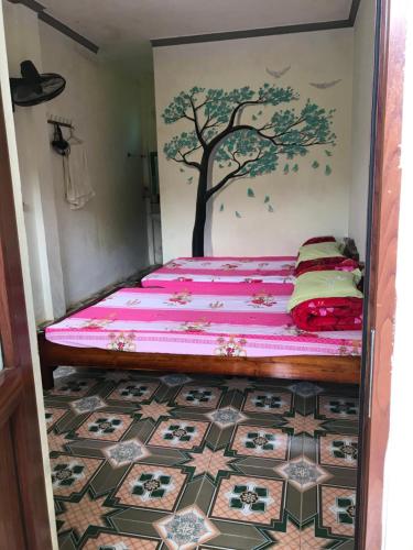 a bedroom with a bed with a tree mural on the wall at Homestay Moc Chau in Mộc Châu