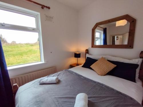 a bedroom with a bed with a mirror and a window at Cosy Cottage by the Sea in Galway