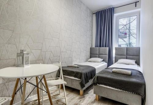 een slaapkamer met 2 bedden en een tafel en een tafel bij MonteFerber Modern Stylish Apartment in Center of Sopot in Sopot