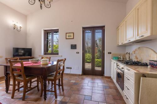 a kitchen with a wooden table and chairs and a kitchen with a stove at Casa Ulmi con piscina in Uggiano la Chiesa