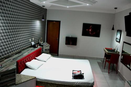 a bedroom with a white bed and a desk and a table at MOTEL COPACABANA in Ribeirão Preto