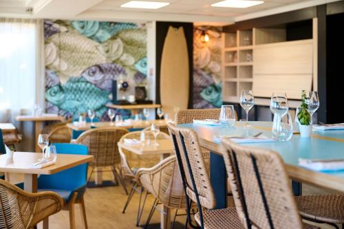 un restaurant avec des tables et des chaises avec des verres à vin dans l'établissement ibis Styles Bordeaux Begles Arena, à Bègles