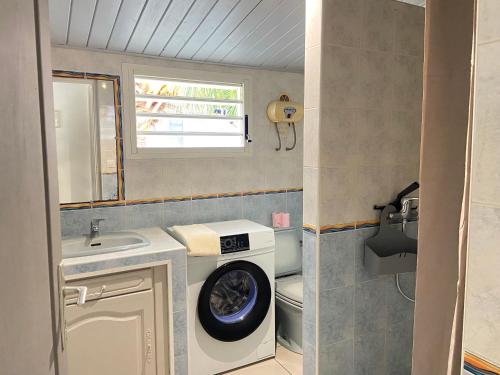 ein Badezimmer mit einer Waschmaschine und einem Waschbecken in der Unterkunft Le Manacoël in Saint-Joseph