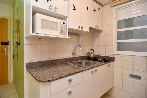 cocina con fregadero y microondas en Apto 1 quadra da Praia em Canasvieiras P2123, en Florianópolis