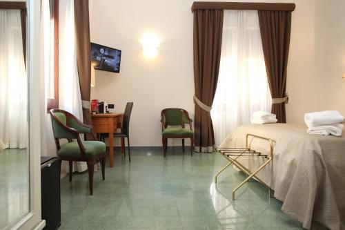 um quarto de hotel com uma cama, uma secretária e cadeiras em Albergo Russo em Trapani