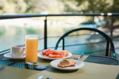 uma mesa com dois pratos de comida e um copo de sumo de laranja em Hotel Nututun Palenque em Palenque