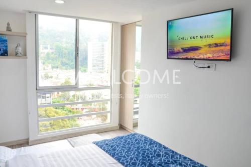 1 dormitorio con ventana grande y TV de pantalla plana en Top Spot Studio, Bogotá, en Bogotá