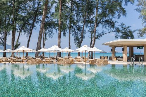 a swimming pool with chairs and umbrellas at InterContinental Phuket Resort by IHG in Kamala Beach