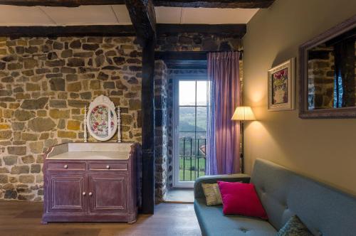 sala de estar con sofá y pared de piedra en Posada Casa Guadamillas 