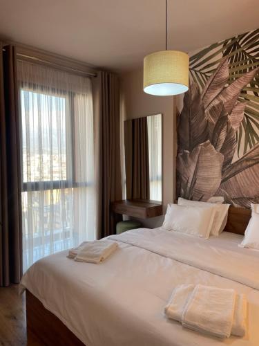 1 dormitorio con 1 cama blanca grande y ventana grande en Erida’s Apartment, en Tirana
