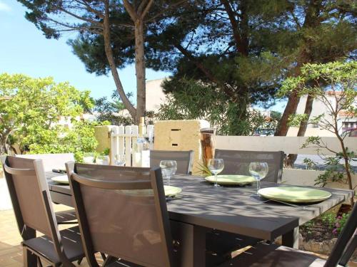 une table noire avec des chaises et une table avec des verres à vin dans l'établissement Maison Familiale 2 Étoiles à 150m de la Plage avec Terrasse, Jardin et Parking Privé - FR-1-229C-673, à Port-la-Nouvelle