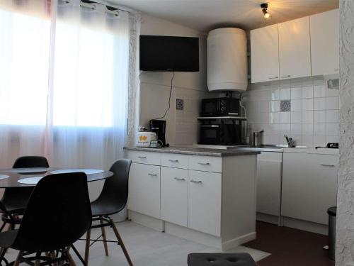 une cuisine avec des armoires blanches et une table avec des chaises dans l'établissement Studio cabine rénové, proche plage et commerces, 4 couchages, Port-la-Nouvelle - FR-1-229C-70, à Port-la-Nouvelle