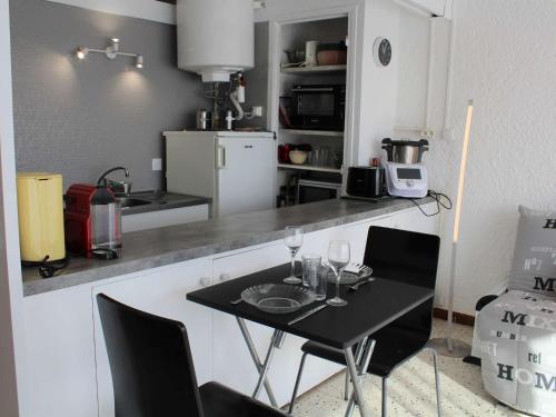 une cuisine avec une table noire et des chaises avec des verres à vin dans l'établissement Studio lumineux à 50m de la plage, grand balcon, parking, animaux acceptés, ménage inclus - FR-1-229C-67, à Port-la-Nouvelle