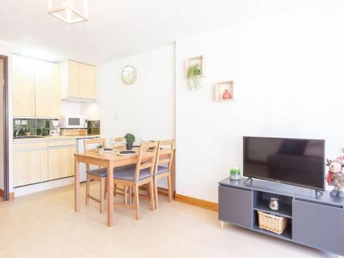 Il comprend une cuisine et une salle à manger avec une table et une télévision. dans l'établissement Studio 4 pers. avec balcon exposé sud, proche commerces et télécabine, Saint-Lary Village - FR-1-296-462, à Saint-Lary-Soulan