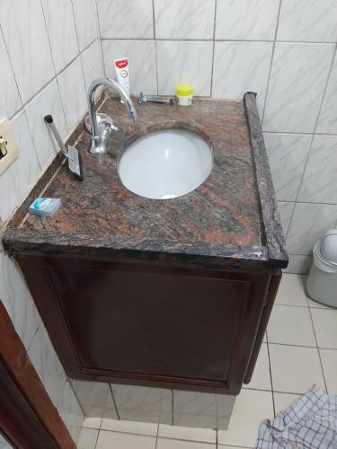 a bathroom sink with a granite counter top at Acordar com o cantar do passaro in Jabuticabal