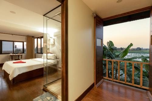 a bedroom with a bed and a balcony with a view at Damnak Phnom Krom Homestay in Phumĭ Rœssei Lŭk