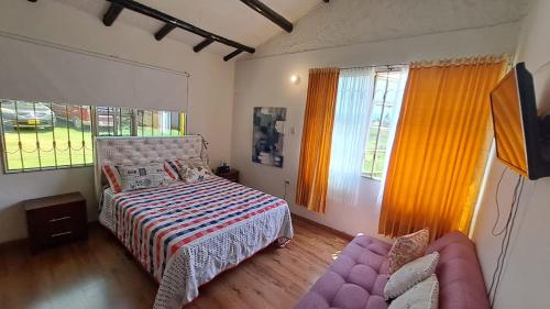 een slaapkamer met een bed, een bank en ramen bij El Rancho in Nobsa