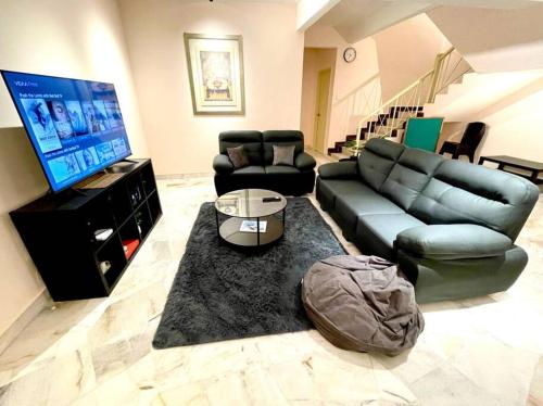 a living room with a black leather couch and a flat screen tv at 6-12pax The Premium House - The Heart Of Sunway in Petaling Jaya