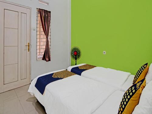 2 Betten in einem Zimmer mit grünen Wänden in der Unterkunft SPOT ON 92255 Lucky Guesthouse in Kubang