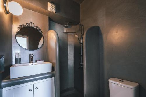 uma casa de banho com um lavatório, um espelho e um WC. em Aspa Villas em Oia