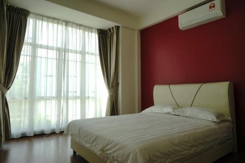 a bedroom with a white bed and a red wall at Likas House @ Alawa Homes in Kota Kinabalu